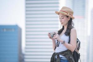 vacker asiatisk turistkvinna tycker om att ta foto med retrokamera på turistsightseeingplats. semesterresor på sommaren.