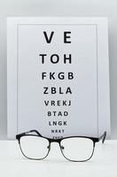 kontroll vision bord med ett par glasögon. ögonläkare tillbehör isolerad på vit bakgrund. foto