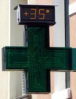 digital gatutermometer på en apoteksskylt som visar 35 grader celsius. mycket varm dag koncept foto