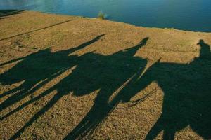 siluett skuggor av människor på hästryggen reflekteras på gräsmattan från en ranch nära cambara do sul. en liten lantlig stad i södra Brasilien med fantastiska naturliga turistattraktioner. foto