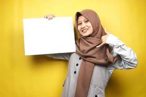 ganska ung muslimsk kvinna gladlynt hållande tom tom banderoll, plakat, vit tavla, tom skylttavla, vit reklamtavla, presentera något i kopia utrymme, marknadsföring foto