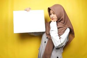 ganska ung muslimsk kvinna som tänker hålla en tom banderoll, plakat, vit tavla, tom skylttavla, vit reklamtavla, presentera något i kopieringsutrymmet, marknadsföring foto