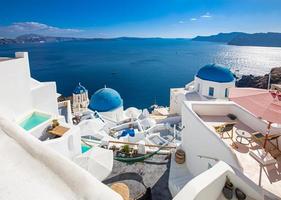 fantastiskt panoramalandskap, lyxresor semester. Oia stad på ön Santorini, Grekland. traditionella och berömda hus och kyrkor med blå kupoler över kalderan, Egeiska havet foto