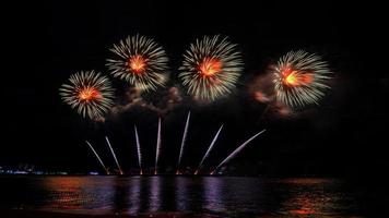 fantastiskt vackert färgstarkt fyrverkeri på festkvällen, som visas på havsstranden med flerfärgad reflektion på vatten foto