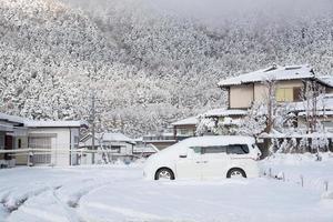 ny vit snö som faller på offentlig park täcker väg och bil under vintersäsongen i kawaguchiko, japan. foto