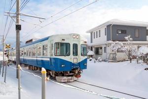 tåg rör sig på järnvägsspåret för lokaltåg med vit snö faller under vintersäsongen, japan foto