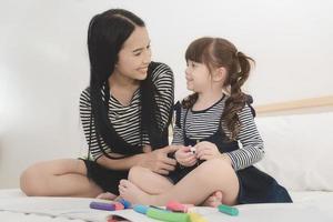 lycklig kärleksfull familj, asiatisk ung mamma leker med sin dotter i barnens rum. fotodesign för familj, barn och glada människor koncept. foto