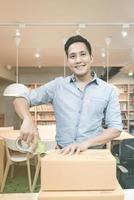 asiatisk entreprenör packar in produkt i lådan för sina kunder efter att ha fått beställning på hemmakontoret. konceptuell för nystartade småföretag som startar eget företag och marknadsföring online. foto