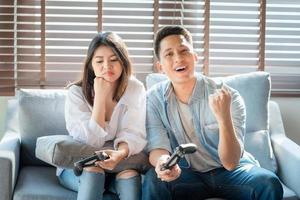 Asiatiska parälskare njuter och spelar konsolspel på semestern gör mer kvalitetstid av lycka tillsammans hemma foto