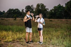 män och kvinnor står för att dricka vatten efter träning. foto