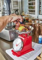 kvinna väger fikon på våg i köket för att göra paj med recept från internet foto
