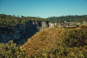 cambara do sul, Brasilien - 16 juli 2019. människor på träbelvedere på kanten av klippan vid itaimbezinho kanjon nära cambara do sul. en liten lantstad med fantastiska naturliga turistattraktioner. foto