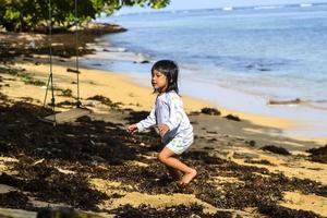 en liten flicka som leker på en gunga vid stranden foto