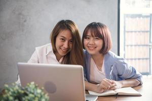 två unga affärskvinnor som sitter vid bordet i kafé. asiatiska kvinnor som använder bärbar dator och kopp kaffe. frilansare som arbetar på kafé. arbetar utanför kontorets livsstil. en-mot-en-möte.