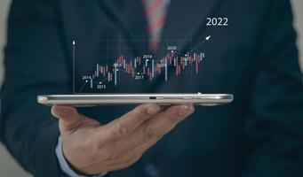 affärsman som håller surfplattan 2022 aktiemarknadsprognos utsikter, diagram och ljusstakar, aktiemarknadens rörelsetrend, tidigare till nutid. foto