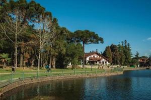 gramado, brasilien - 21 juli 2019. trädbevuxen park med sjön joaquina rita bier och gammalt hus i tysk stil på gramado. en söt europeisk influerad stad mycket eftertraktad av turister. foto