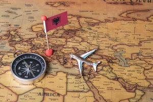 Albaniens flagga, kompass och flygplan på världskartan. foto