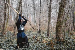 man utövar kendo med shinai bambu svärd på skog bakgrund foto