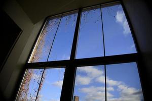 blå himmel och moln genom ett fönster i en byggnad foto