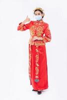 kvinna bär cheongsam kostym och mask visar det bästa sättet att handla för att skydda sjukdom