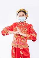kvinna bär cheongsam kostym och mask välkommen klient att handla i kinesiska nyåret foto