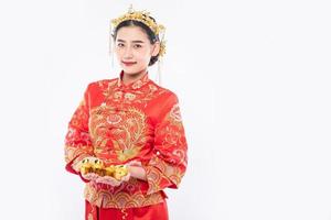 kvinna bär cheongsam kostym och krona ger guld till sin familj för tur i kinesiska nyåret foto