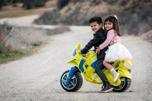 liten pojke och flicka som rider på motorcykelleksak foto