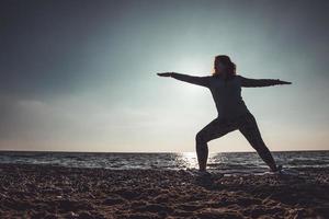 ung kvinna gör yoga och stretching på stranden foto