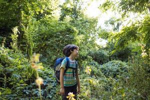 en pojke med ryggsäck går genom skogen foto