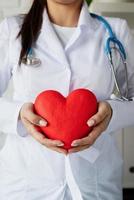 läkare eller forskare kvinna som håller stort rött hjärta i händerna foto