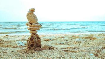 stenar balanserade på ren sand med strandbakgrund som visar begreppet harmoni foto