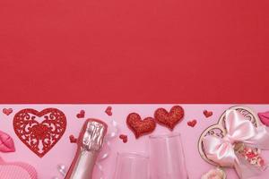 ovanifrån två glas, röda hjärtan, champagne, blommor på en rosa-röd bakgrund med kopia utrymme alla hjärtans dag datum eller fest koncept foto
