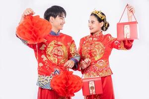 män och kvinnor som bär cheongsam står och håller röd väska och honeycomb lykta foto