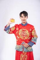 man som bär en cheongsam håller ett kreditkort för att shoppa under det kinesiska nyåret. foto