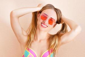 mode porträtt vacker kvinna i sommar röda solglasögon över färgglada persika bakgrund foto