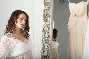 flicka i en vit klänning vid spegeln. foto