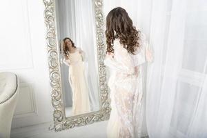 flicka i en vit klänning vid spegeln. foto