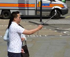 london, england, 2014, glada turister tar en selfie på Londons gator. människor som har roligt med ny teknik. foto