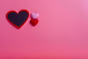rött hjärta i tre olika storlekar på vänster sida i rosa bakgrund. alla hjärtans dag koncept. minimal stil koncept foto