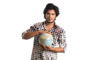 ung man med en världsglob på en vit bakgrund. foto
