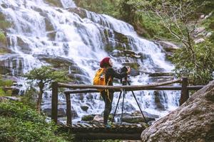 asiatisk kvinna reser koppla av för att fotografera de vackra vattenfallen. på vintern. vid vattenfallet mae ya chiangmai i thailand. reser naturen. sommar foto