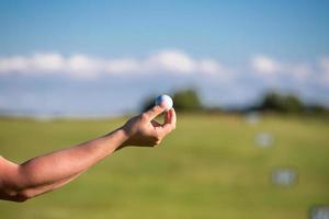 en person som håller en golfboll i bakgrunden av golfbanans golfkoncept foto