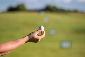 en person som håller en golfboll i bakgrunden av golfbanans golfkoncept foto