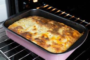 lasagne i en bakform, tagen ur ugnen. beredning av en traditionell italiensk maträtt. foto