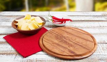 kryddig röd chili potatischips och tom bräda på ett träbord foto