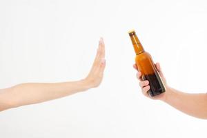 kvinnlig hand avvisa en flaska öl isolerad på vit bakgrund. anti alkohol koncept. kopieringsutrymme foto
