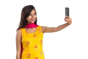 ung indisk flicka som använder en surfplatta, mobiltelefon eller smartphone isolerad på en vit bakgrund foto
