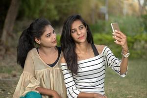 två vackra kvinnliga vänner som tar selfie med smartphone utomhus. foto