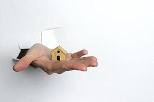 kvinnlig hand som håller ett hus på en vit bakgrund.