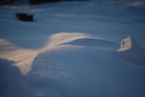 snöiga landskap och snö närbild i solstrålar. gräs och föremål i snön. foto